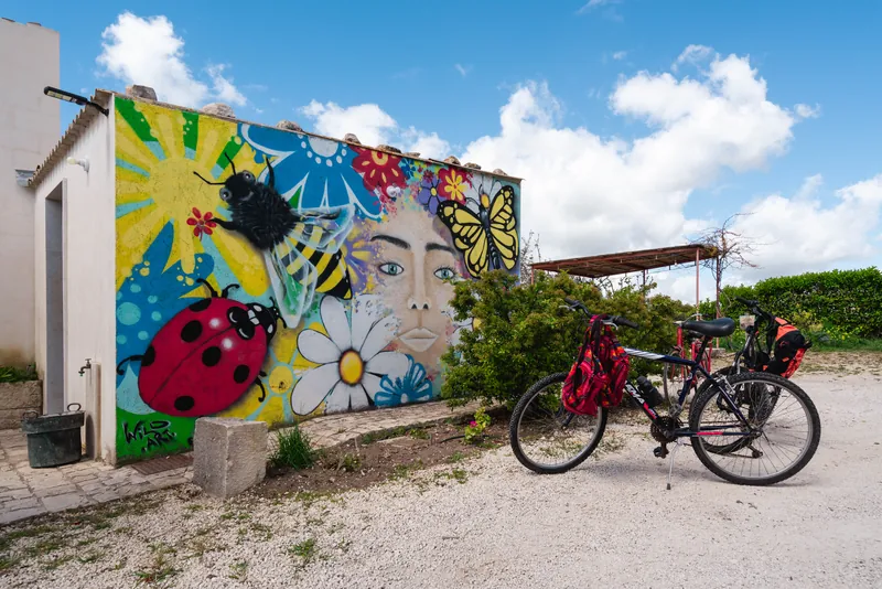 Biciclette appoggiate davanti al murale colorato della casa